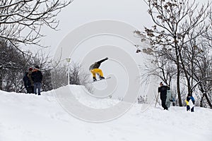 Kid jumping over a hill made of snow with snowboard