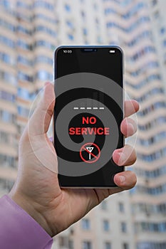 No Service notification on the cell phone screen. Smartphone in man`s hand against the background of a residential