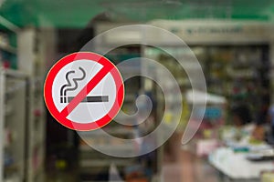 No smoking area sign at the glass door of drug store.