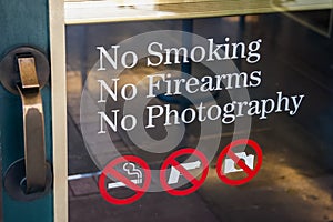 No Smoking, No Firearms, No Photography sign at the door entrance