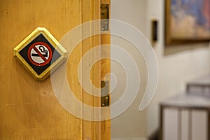 No smoking sign against a wood wall. The white non-smoking sign on the wooden floor is a sign that the traveler is aware of being