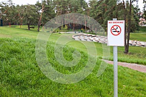 No smoking sign in a green park. Label no smoking metal sign in the park. Copy space for text, mockup