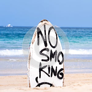 No Smoking warning sign on white surfboard at the beach in summer, concept of sea environmantal protection design, copy space,