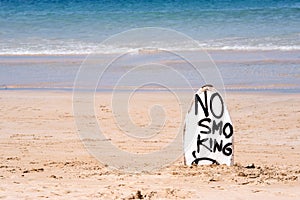 No Smoking warning sign on white surfboard at the beach in summer, concept of sea environmantal protection design, copy space,