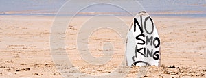 No Smoking warning sign on white surfboard at the beach in summer, concept of sea environmantal protection design, copy space,