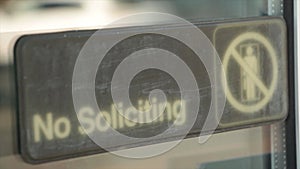 no soliciting horizontal sign on glass window with reflection of vehicle car