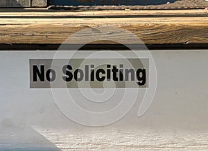A No Soliciting sign placed elegantly on home entrance wooden stairs.