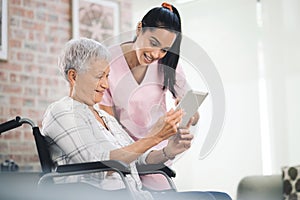 No step too small. a young nurse sharing information from her digital tablet with an older woman in a wheelchair.