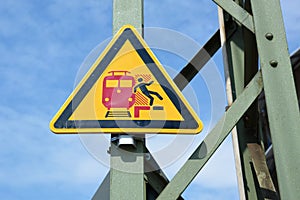 `No stepping over red line` yellow triangular warning signn at German train station showing stylized person falling off platform photo