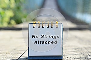 No strings attached text written on white note with blurred background of hanging bridge