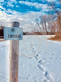No swimming sign with foot prints in snow
