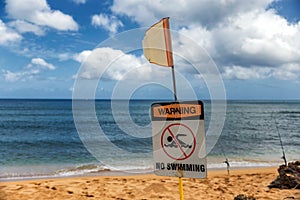 No swimming warning sign and red flag on the beach in Haleiwa