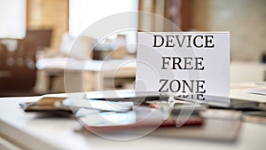 No tech allowed. Close up of mobile phones on the office table with device free zone sign photo