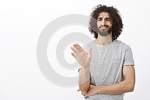 No thanks, I pass. Displeased uninterested handsome curly-haired male in stylish striped t-shirt, waving palm in no or