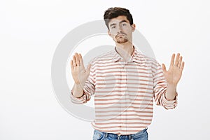 No thanks. Portrait of indifferent unconcerned attractive male with gloomy face, pulling palms in stop or enough gesture