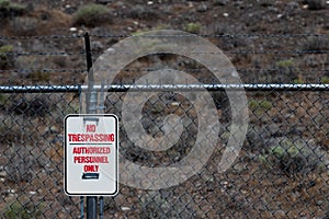 No trespassing authorized personnel sign on a chain link barbed wire fence