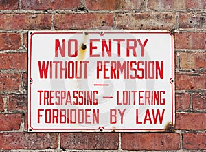 No trespassing sign mounted on brick wall