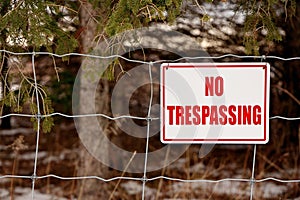 No Trespassing Sign Posted on a Wire Fence in a Rural Setting photo