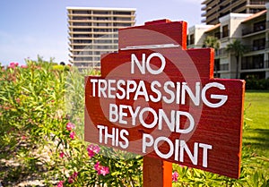 No Trespassing sign in red by flower gardens