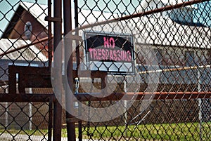 No trespassing sign on a rusted chain link fence