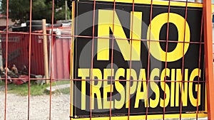 no trespassing signs on orange locked gate for dirt yard parking lot..