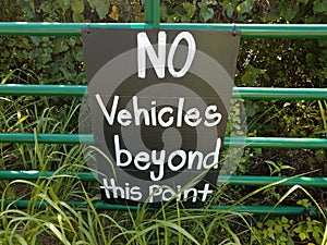 no vehicles beyond this point sign on metal fence