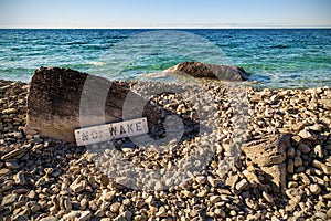 A `No Wake ` sign at a rocky beach in Ontario