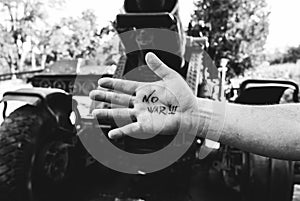 No war sign concept is written on the hand palm. Man is standing near the oltd cannon from the Second World in the green forest.