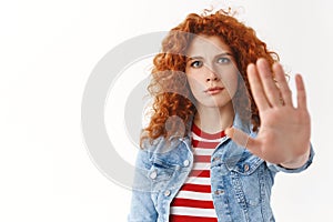 No way not my watch. Serious-looking displeased gloomy redhead curly-haired woman stretch palm camera taboo forbid photo