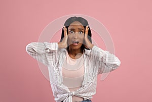 No way. Shocked black woman grasping her head in disbelief over pink studio background