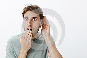 No way, tell me everything. Portrait of shocked and amazed handsome guy with fair hair, dropping jaw, covering opened