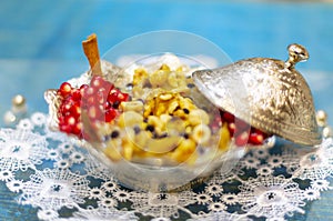Noah`s pudding in white bowl. The dried fruits, legumes and cereals are made with wheat and sugar. It is decorated with walnut, dr