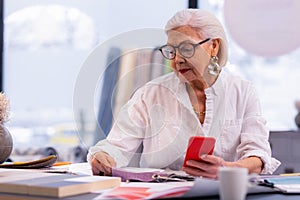 Noble elderly CEO checking textile quality at her office desk