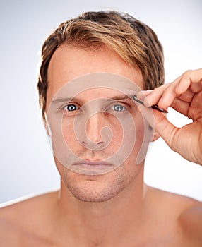 Nobody likes bushy eyebrows. Cropped studio shot of a man concentrating on tweezing his eyebrows.