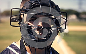 Because nobody likes getting smashed by a ball. Portrait of a young man wearing a catchers helmet while playing a game