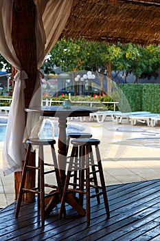 Nobody seat at the wooden stool at the restaurant open air at noon near by a pool