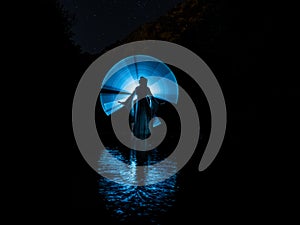 Nocturnal photography, lightpainting, representing a model in the river with shadows made with lanterns on the river