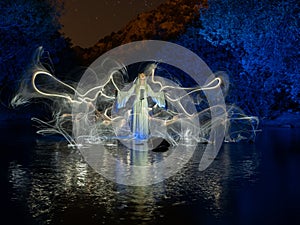 Nocturnal photography, lightpainting, representing a model in the river with shadows made with lanterns on the river