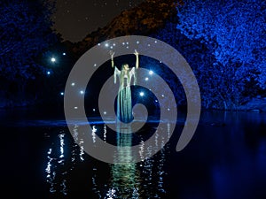 Nocturnal photography, lightpainting, representing a model in the river with shadows made with lanterns on the river