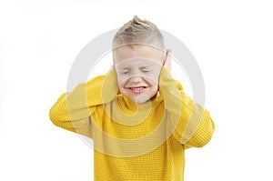 Noise, stress and people concept - stressed boy in yellow sweater closing ears by hands photo