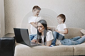 Noisy children distract mothers from working at the computer. annoyed mom holds her head photo