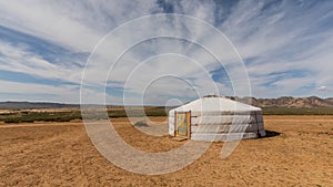 A nomad's white yurt stands in the yellow Gobi desert in Mongolia.