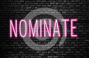 Nominate glowing pink neon sign on black brick wall. Business winner achievement concept for Election Nomination photo