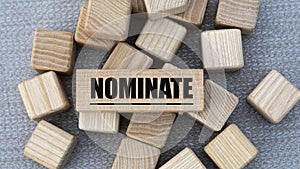 NOMINATE - word on wooden bars on cubes on a gray background photo