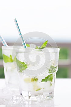 Non alcohol cold mojito cocktail with fresh lime, mint and crushed ice on a white plate