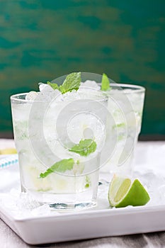 Non alcohol cold mojito cocktail with fresh lime, mint and crushed ice on a white plate