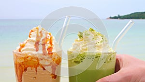 Non-alcoholic drinks in ocean summer cafe. Hand puts detox green cocktail with transparent eco straw on table in summer