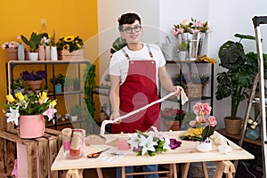 Non binary man florist smiling confident holding gift lace at flower shop