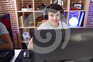 Non binary man streamer playing video game using computer at gaming room