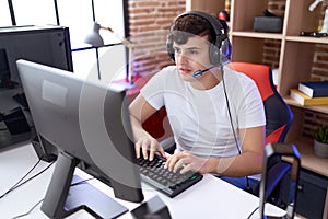 Non binary man streamer playing video game using computer at gaming room